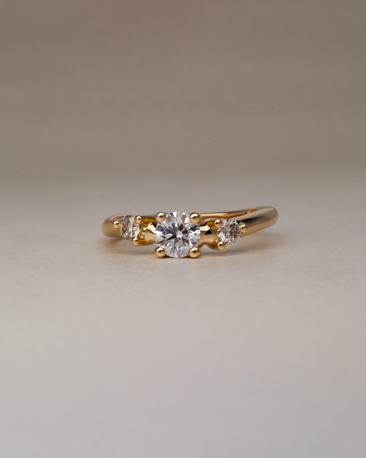 Bespoke wavy trilogy engagement ring in 18K yellow gold with 0.46ct round brilliant natural diamond and champagne diamond side stones — handcrafted by Benjamin Rose Melbourne