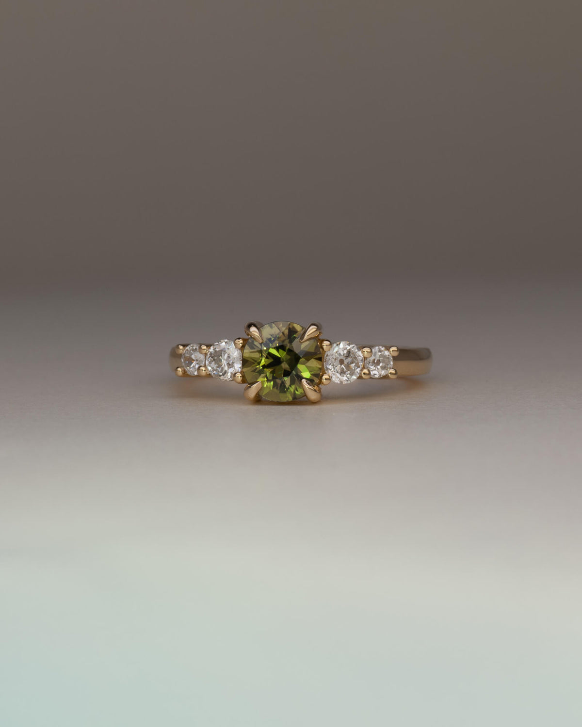 Bespoke five stone engagement ring in 18K yellow gold with 0.86ct round Australian sapphire and natural heirloom diamond side stones — handcrafted by Benjamin Rose Melbourne