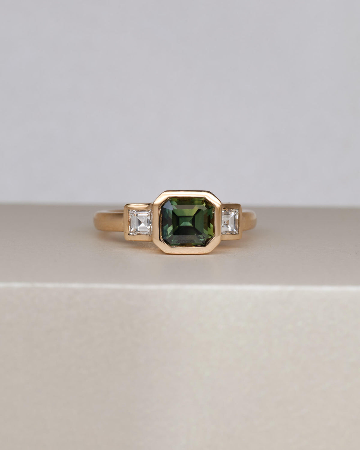 Bespoke sapphire trilogy engagement ring in 18K yellow gold with 1.48ct Australian sapphire and carré cut diamond side stones — handcrafted by Benjamin Rose Melbourne