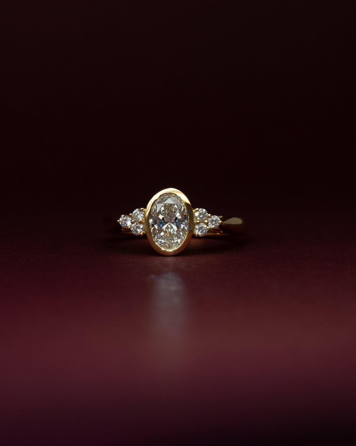 Bespoke seven stone engagement ring in 18K yellow gold with 0.71ct oval natural diamond and round brilliant natural diamond side stones — handcrafted by Benjamin Rose Melbourne